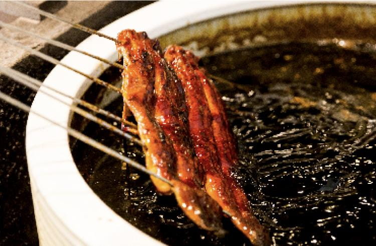 うなぎをたれにくぐらせている様子